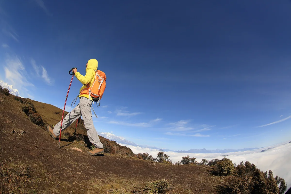young woman backpacker climbing to mountain peak