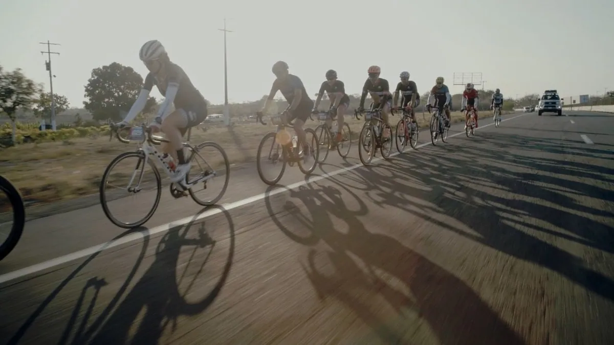 Grupo de ciclistas avanza por una carretera a contraluz.