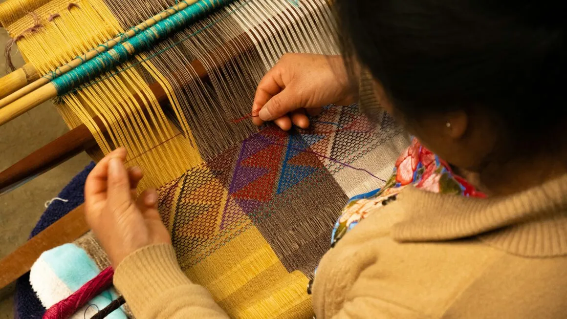 Una persona trabaja con hilos de colores en un telar.