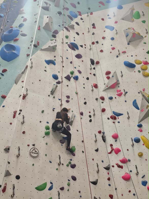 Una persona asciende por un muro de escalada interior