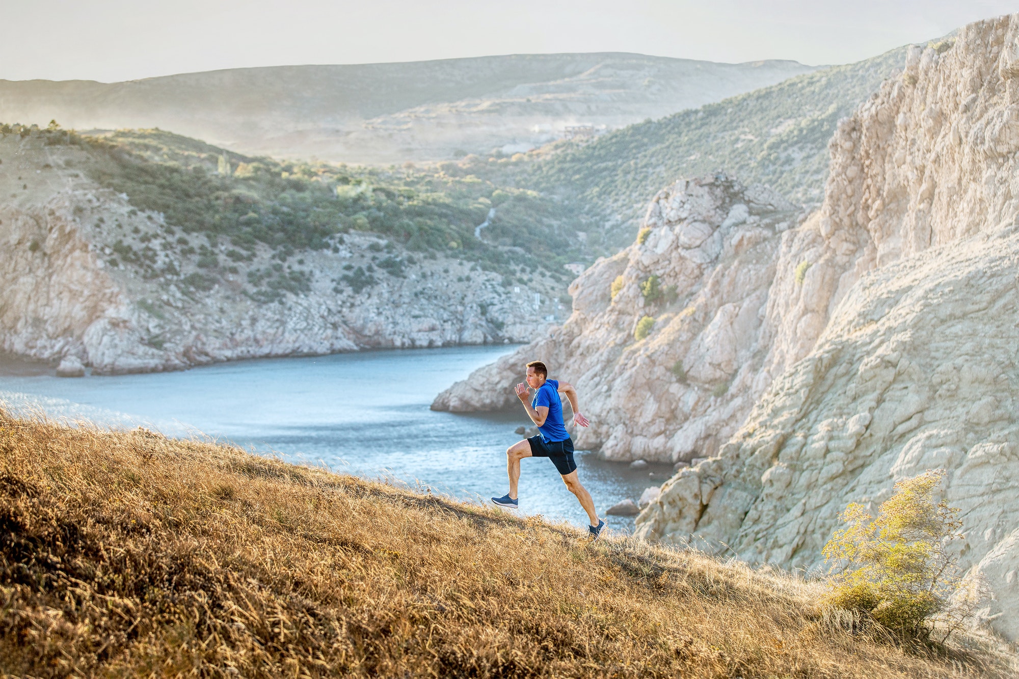 middle-aged man running uphill on trail